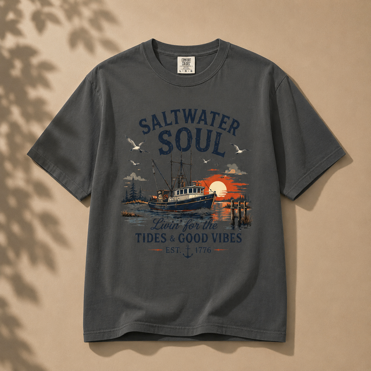 A dark gray crewneck t-shirt with a vintage-style nautical graphic on the front. The graphic features the text 'SALTWATER SOUL' and 'Loin for the Tides & Good Vibes EST.