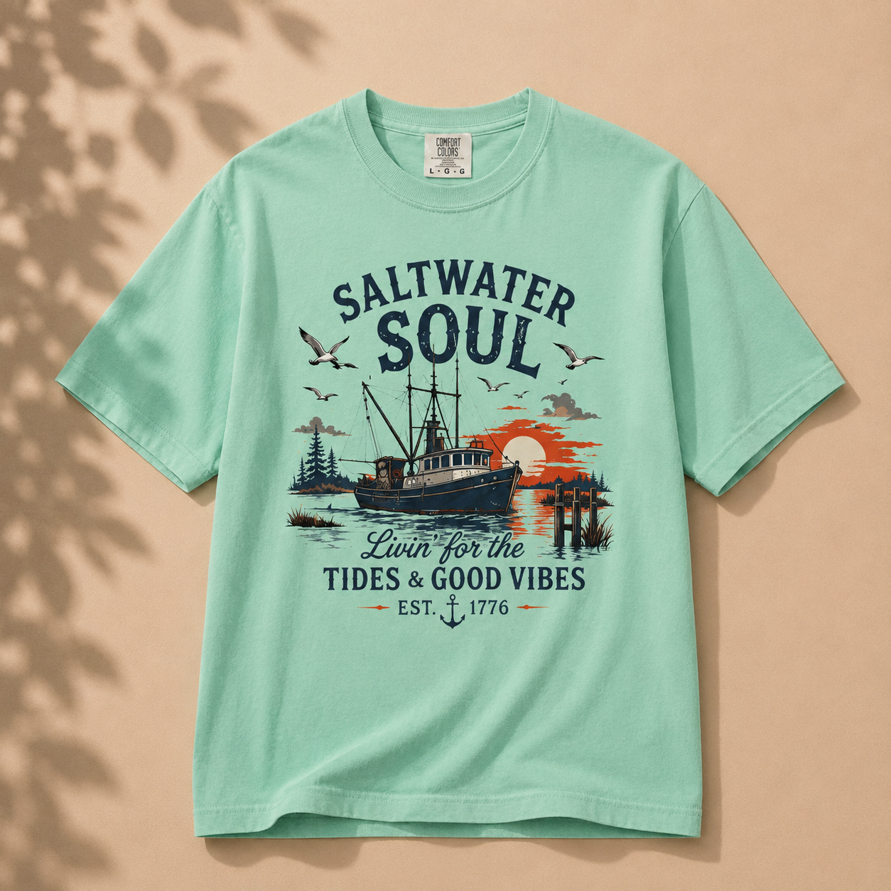 A mint green short-sleeve t-shirt with a vintage-style nautical graphic on the front. The graphic features the text 'SALTWATER SOUL' and 'Loin for the TIDES & GOOD VIBES EST.