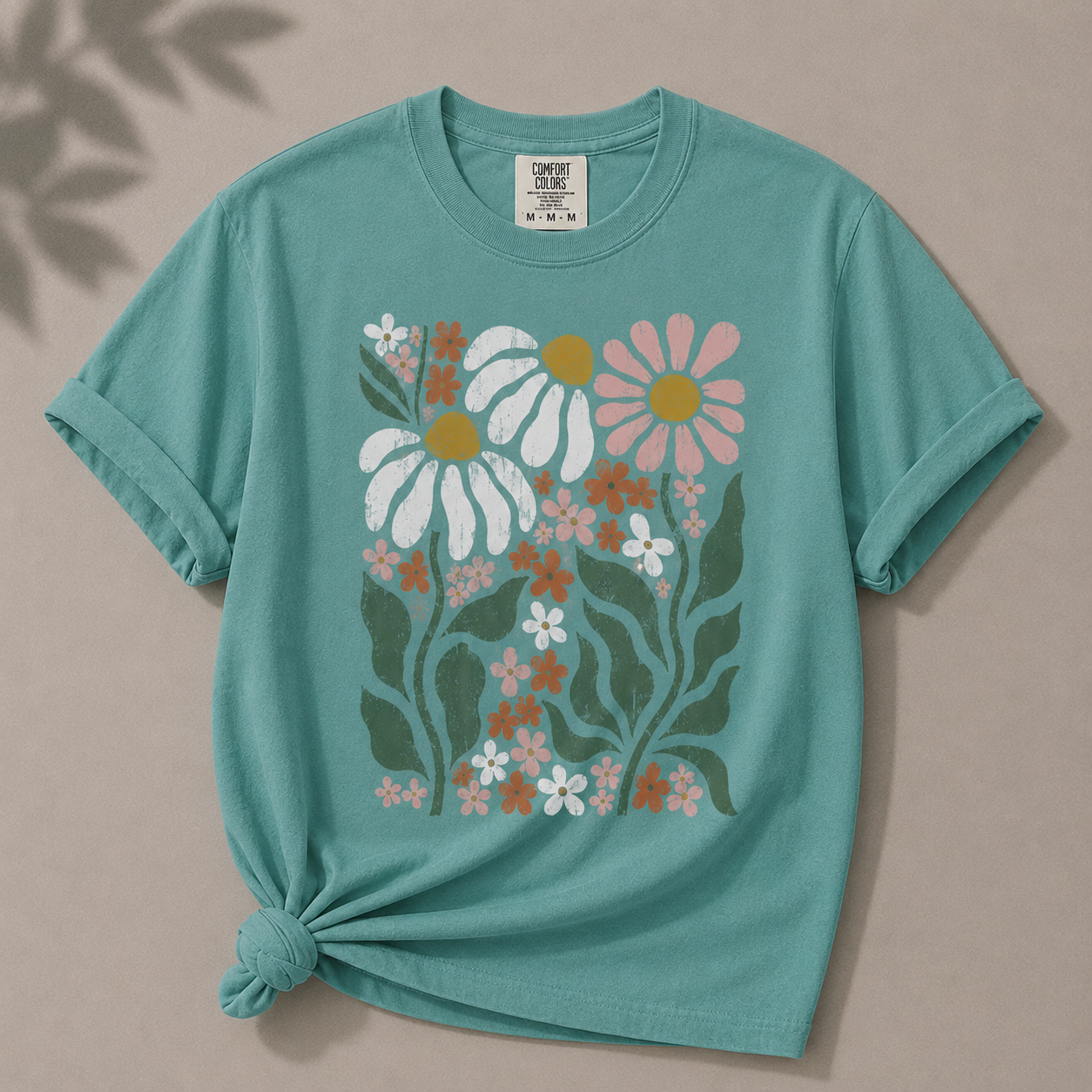 Teal t-shirt with floral design on a beige background