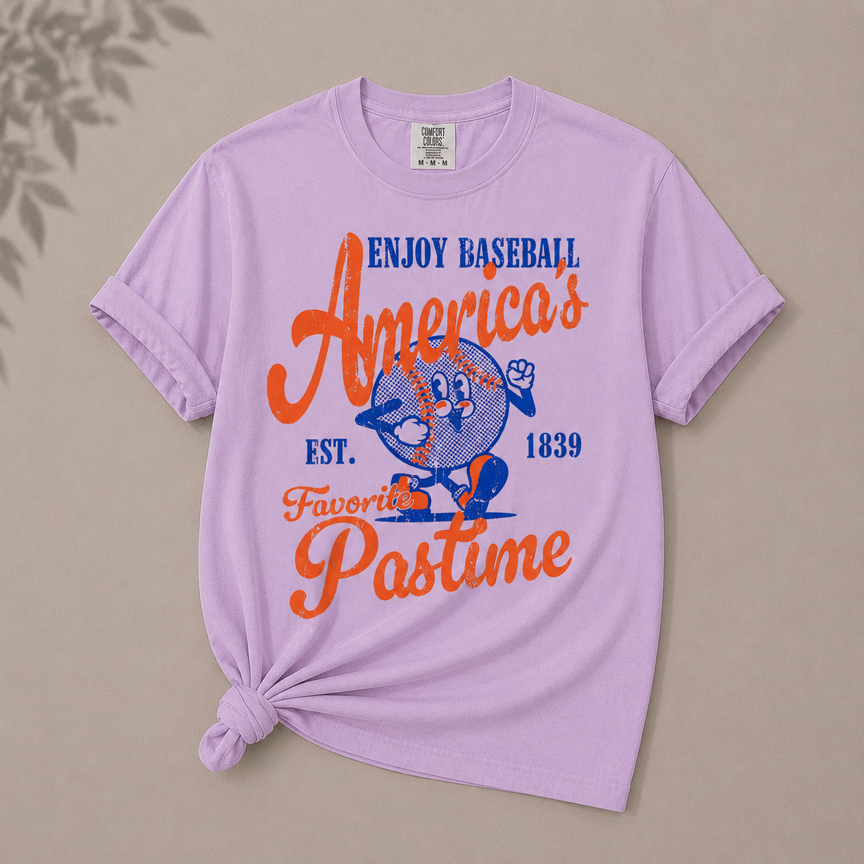 Purple t-shirt with baseball-themed graphic and text on a beige background