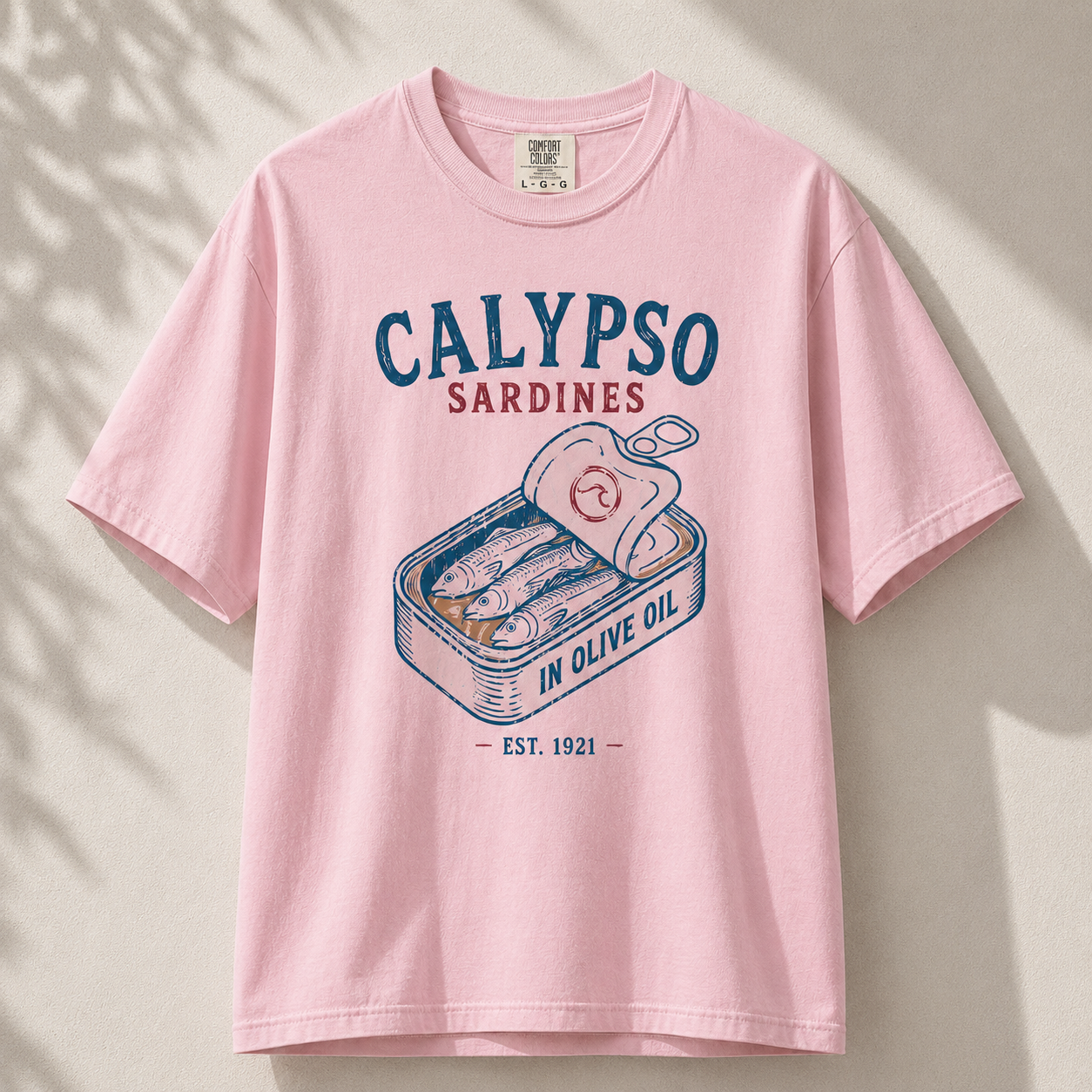 Pink t-shirt with 'Calypso Sardines' graphic on a light background