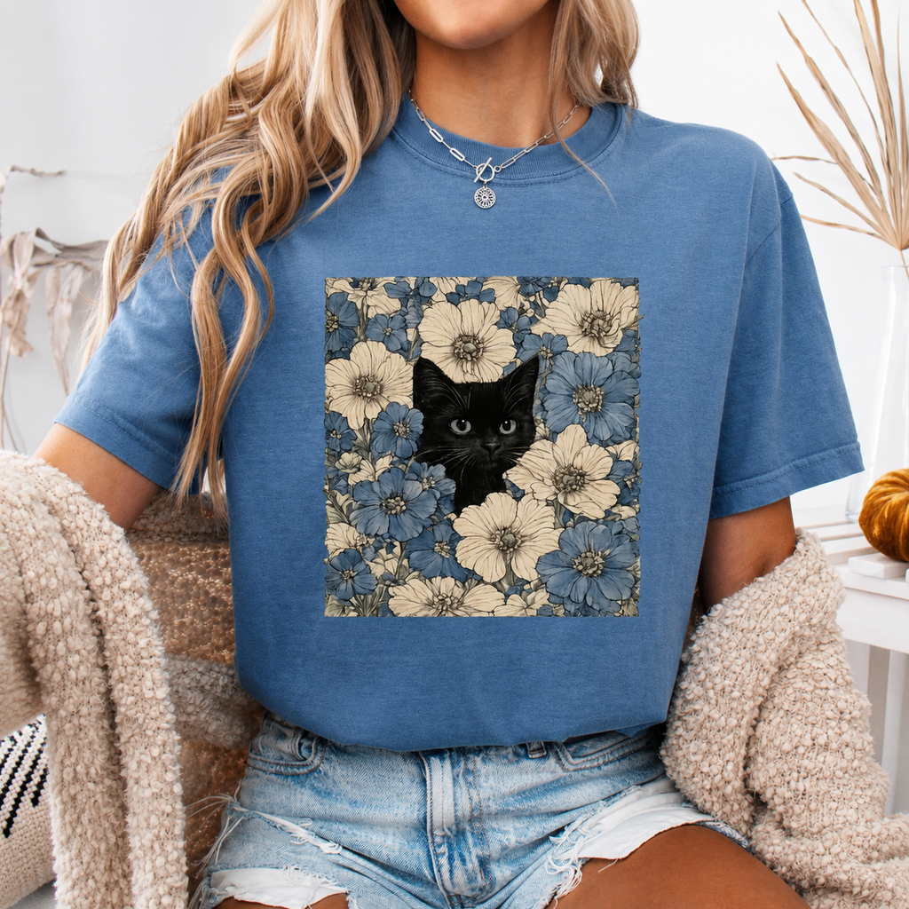 Person wearing a blue t-shirt with a floral and black cat design.