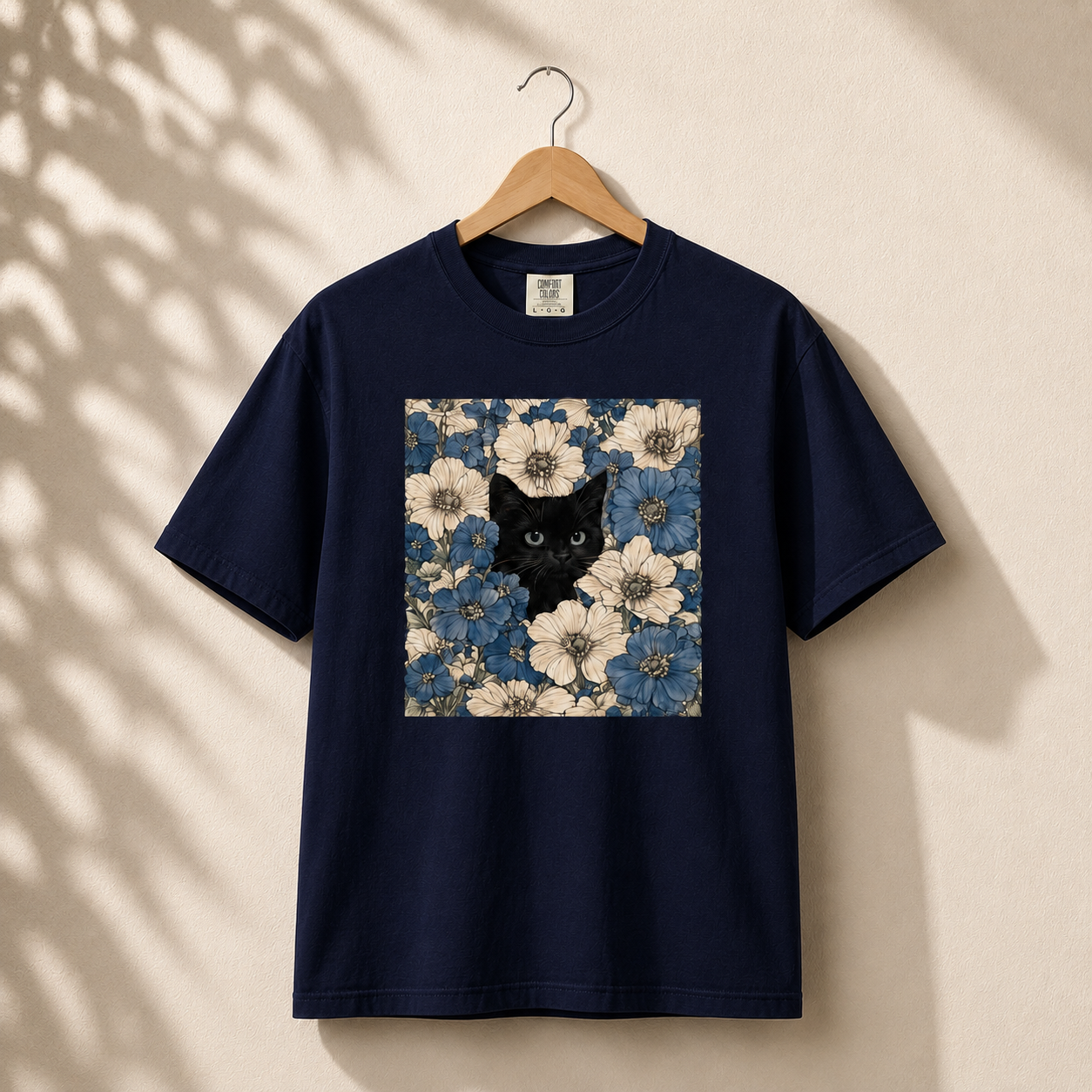 Navy blue t-shirt with a black cat and floral design on a beige background
