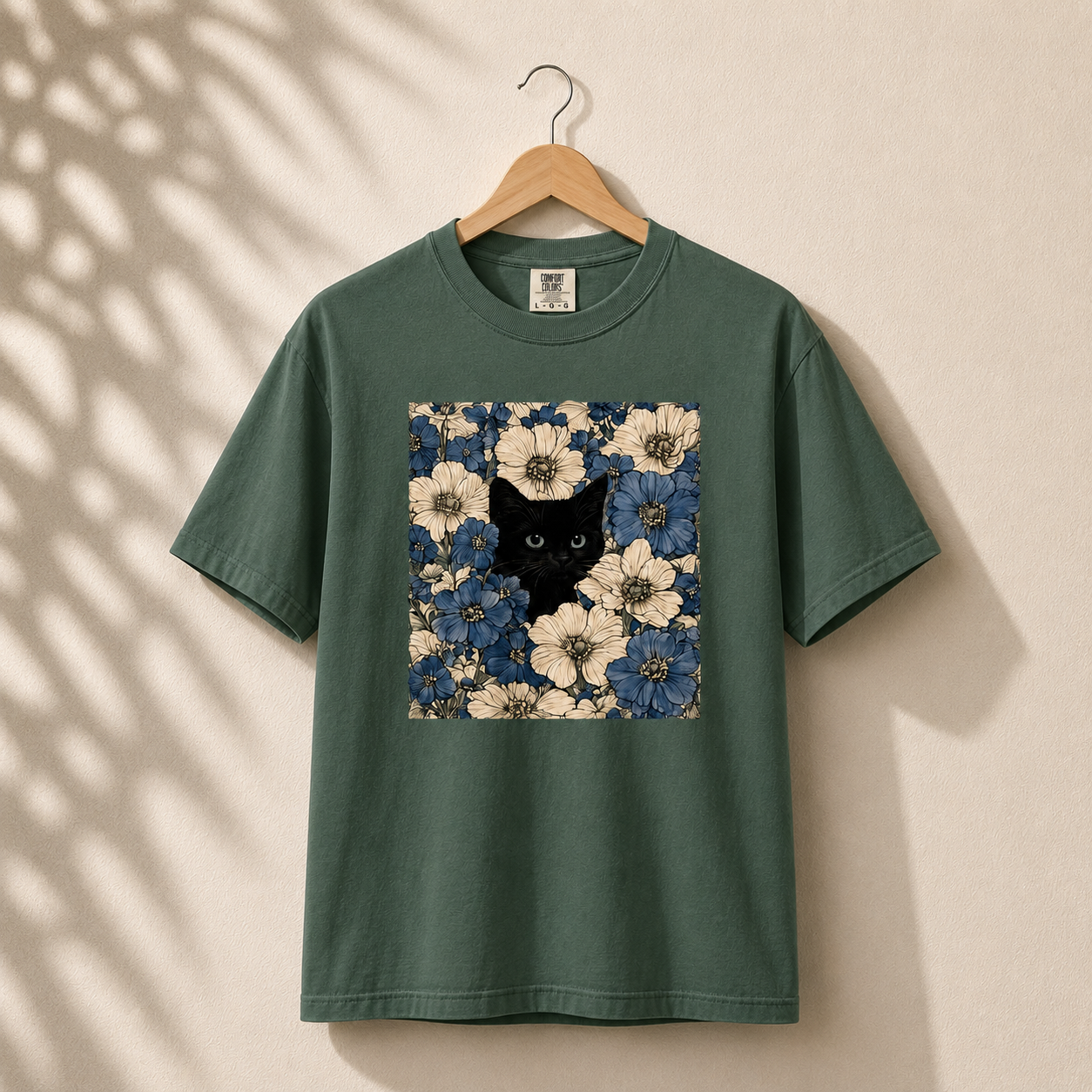 Green t-shirt with a black cat and floral design on a beige background