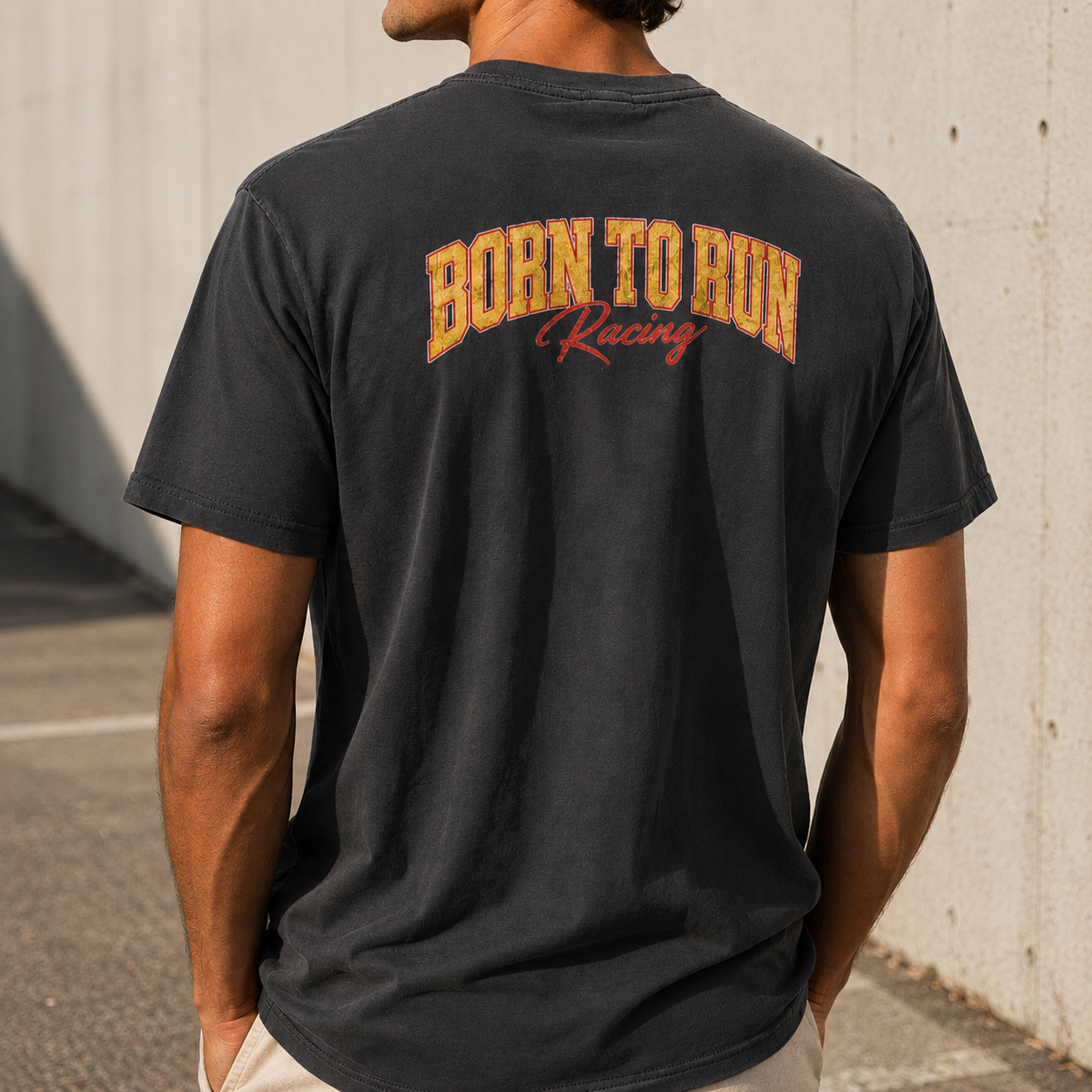 Person wearing a black t-shirt with 'Born to Run Racing' text on the back, standing against a light-colored wall.