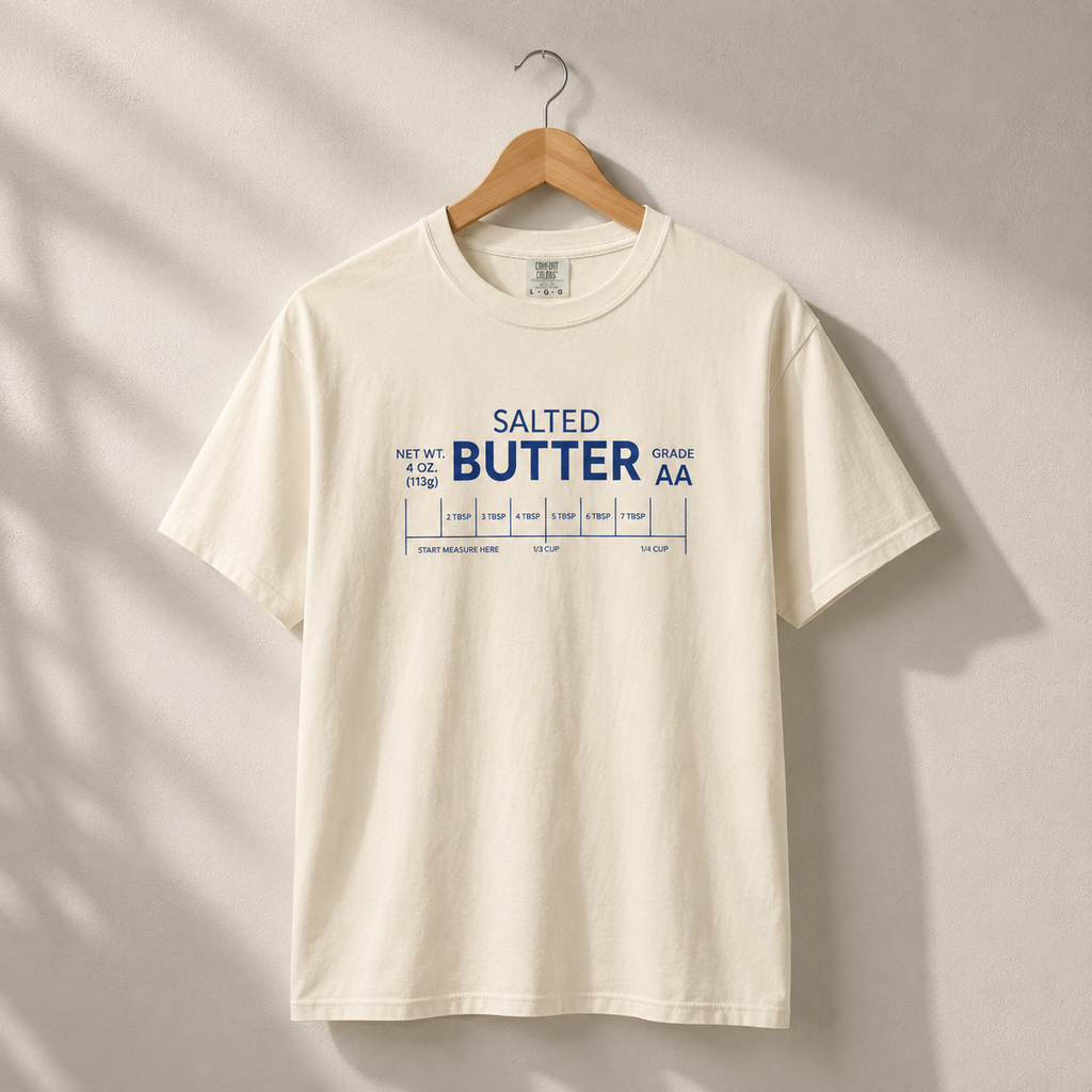 Beige t-shirt with 'Salted Butter Grade AA' text on a hanger against a neutral background