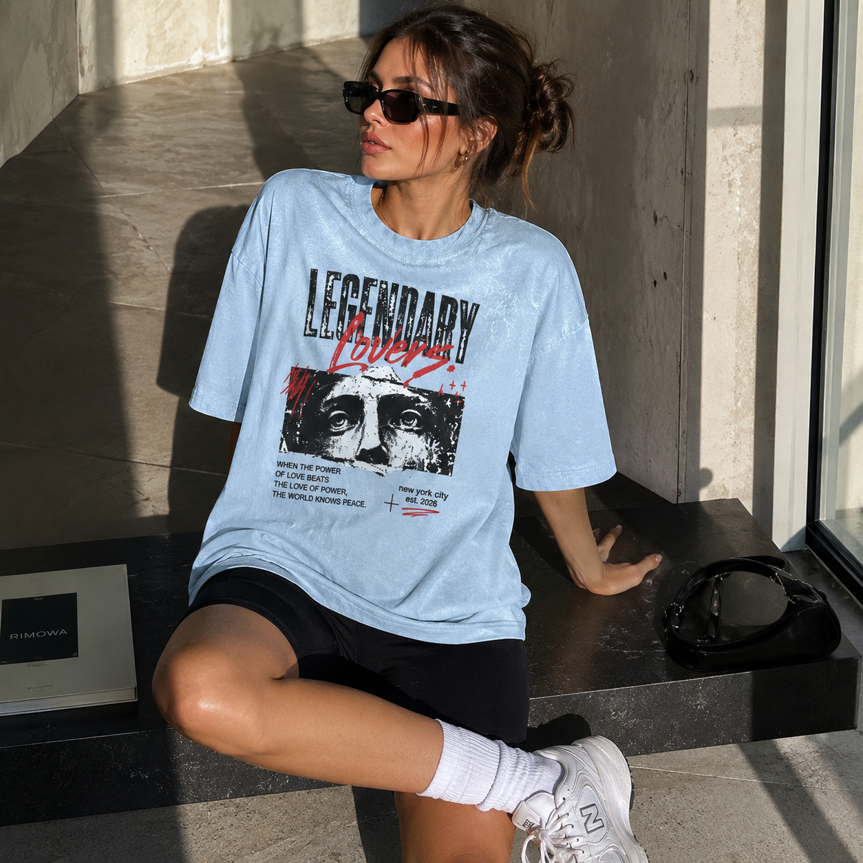 Young woman wearing the Legendary Lovers oversized graphic T-shirt in Water Blue, styled in a modern minimalist lifestyle setting.