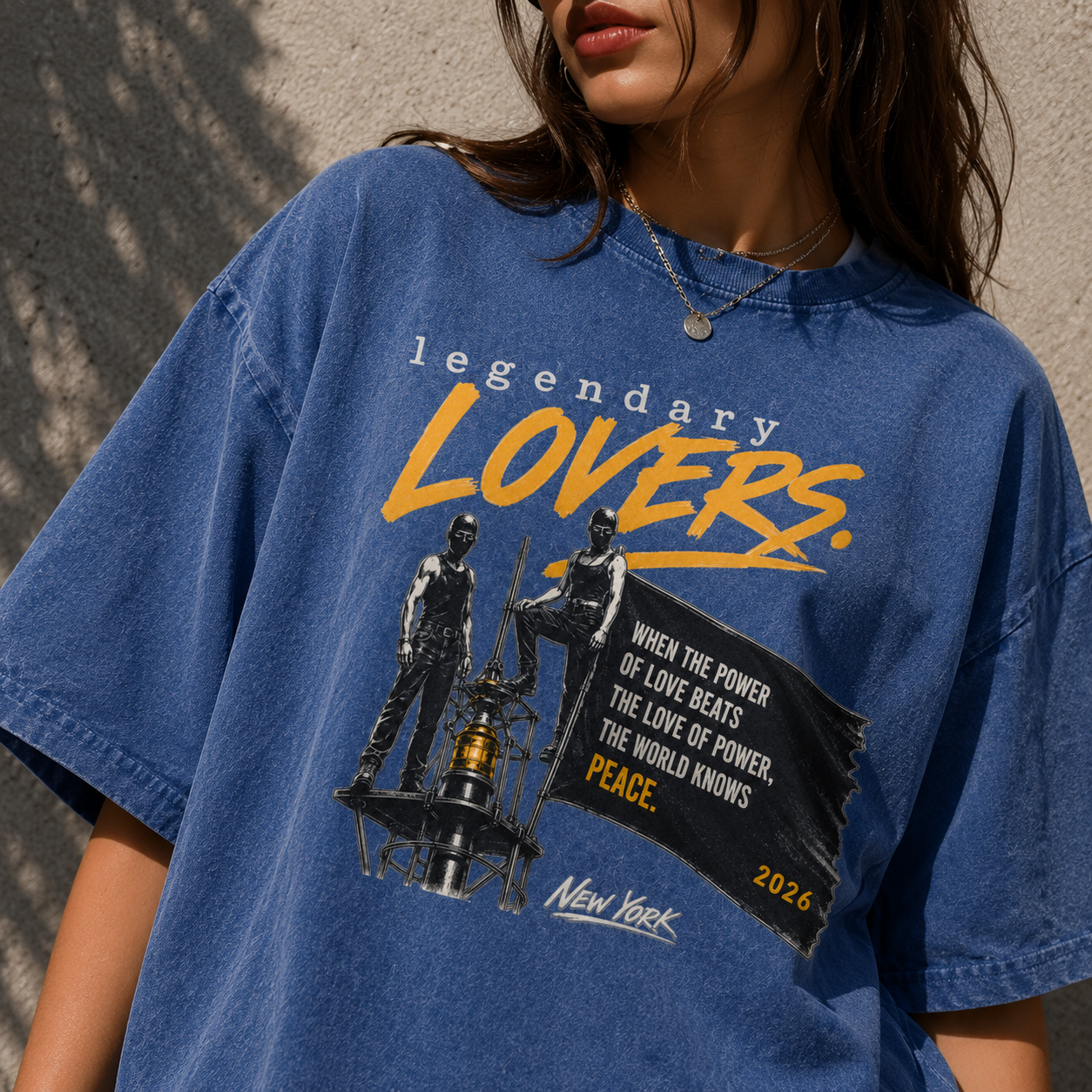 Lifestyle mockup of a model wearing the Legendary Lovers oversized snow washed t-shirt in Dark Blue featuring a bold vintage grunge graphic with yellow typography, peace quote and New York artwork. Unisex streetwear oversized tee.
