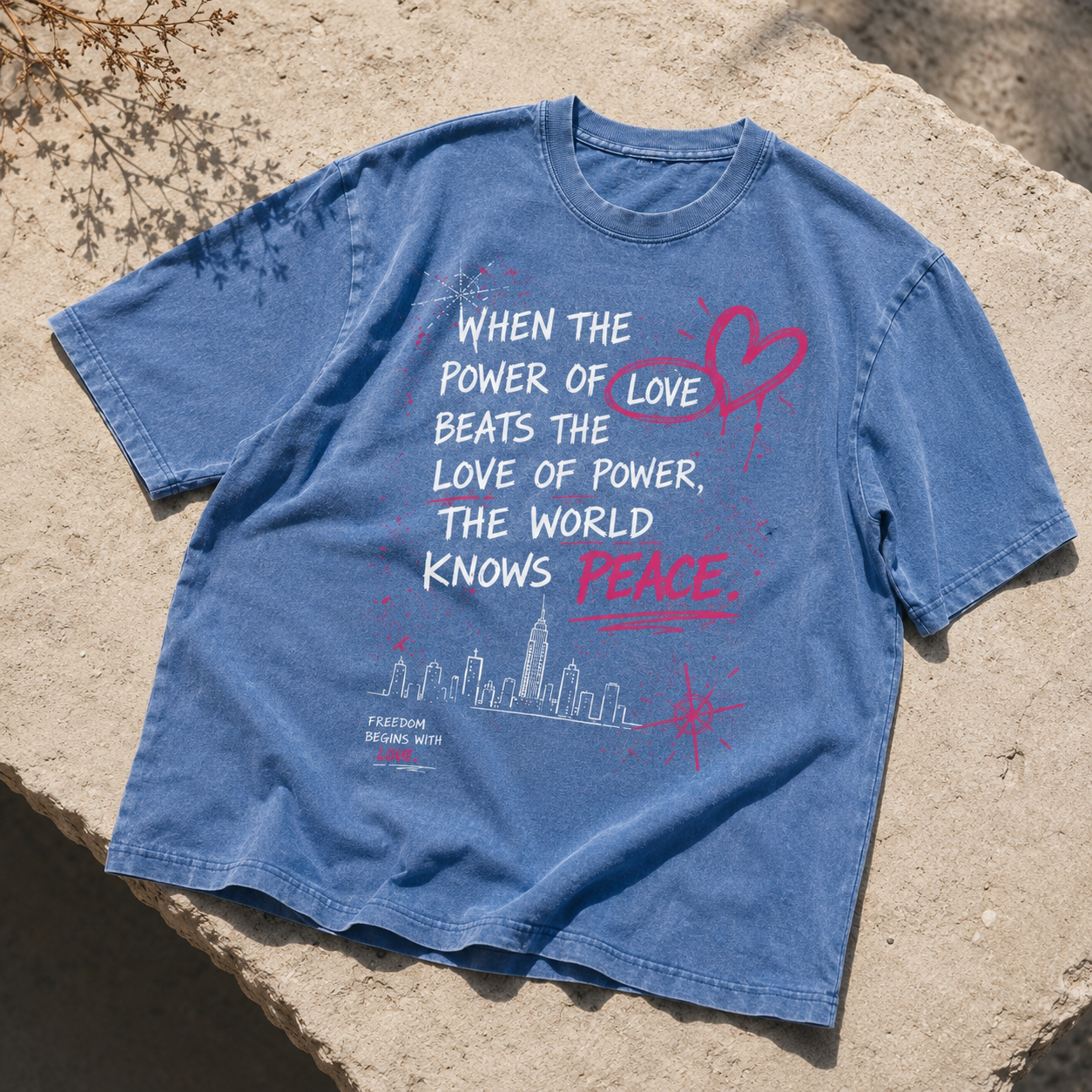 Light blue snow washed oversized graphic t-shirt featuring the "When the Power of Love Beats the Love of Power" design, premium heavyweight cotton unisex streetwear tee with a faded wash finish.