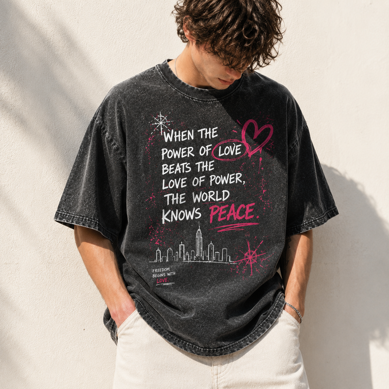 Model wearing a black snow washed oversized graphic t-shirt featuring the "When the Power of Love Beats the Love of Power" design, premium heavyweight cotton unisex streetwear tee with a relaxed oversized fit.