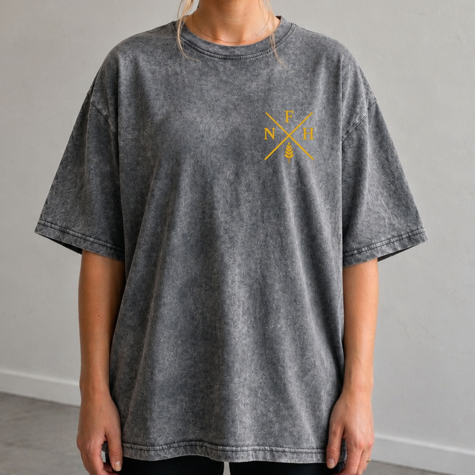 Person wearing a gray t-shirt with a yellow logo on a plain background