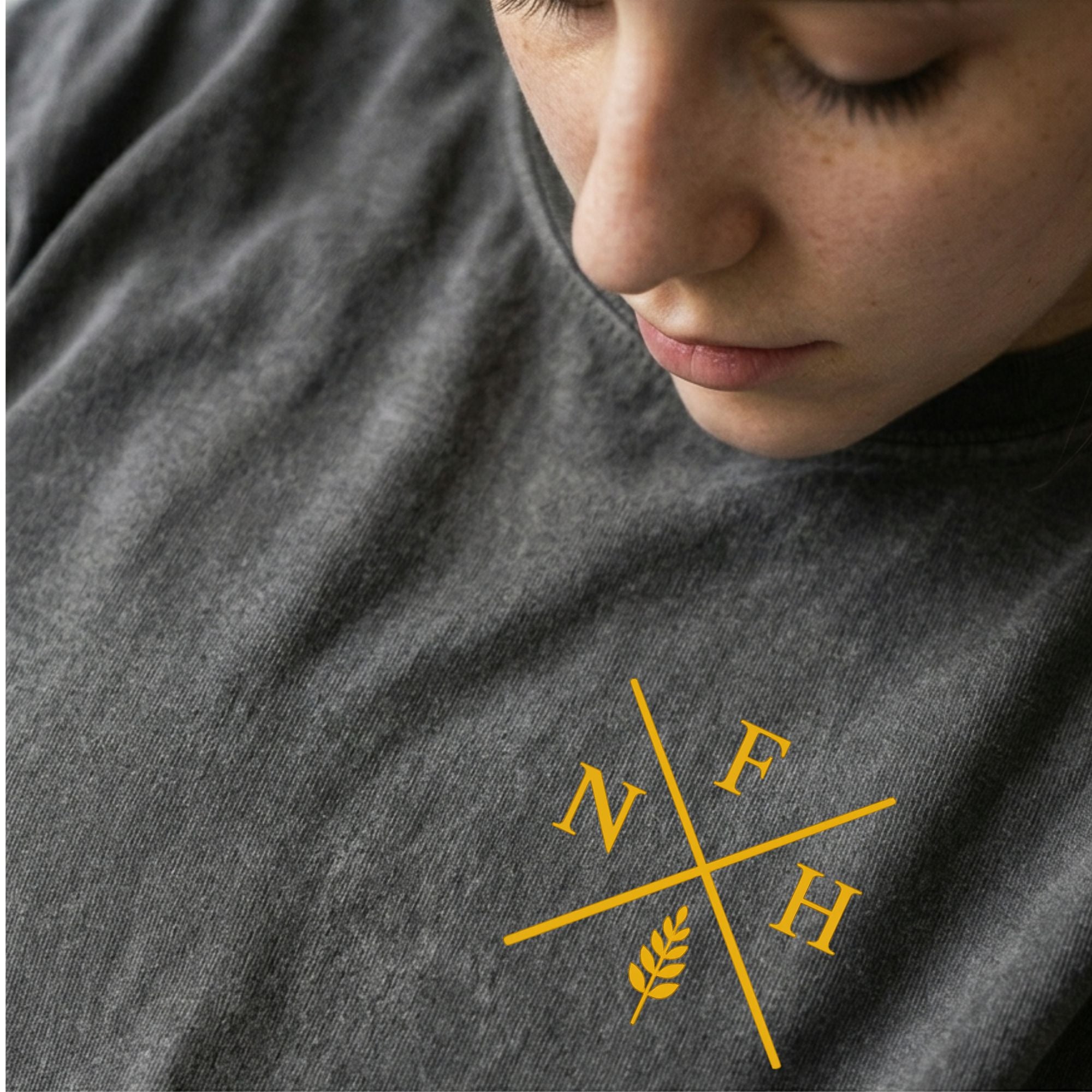 Person wearing a dark gray t-shirt with a yellow logo on the chest.