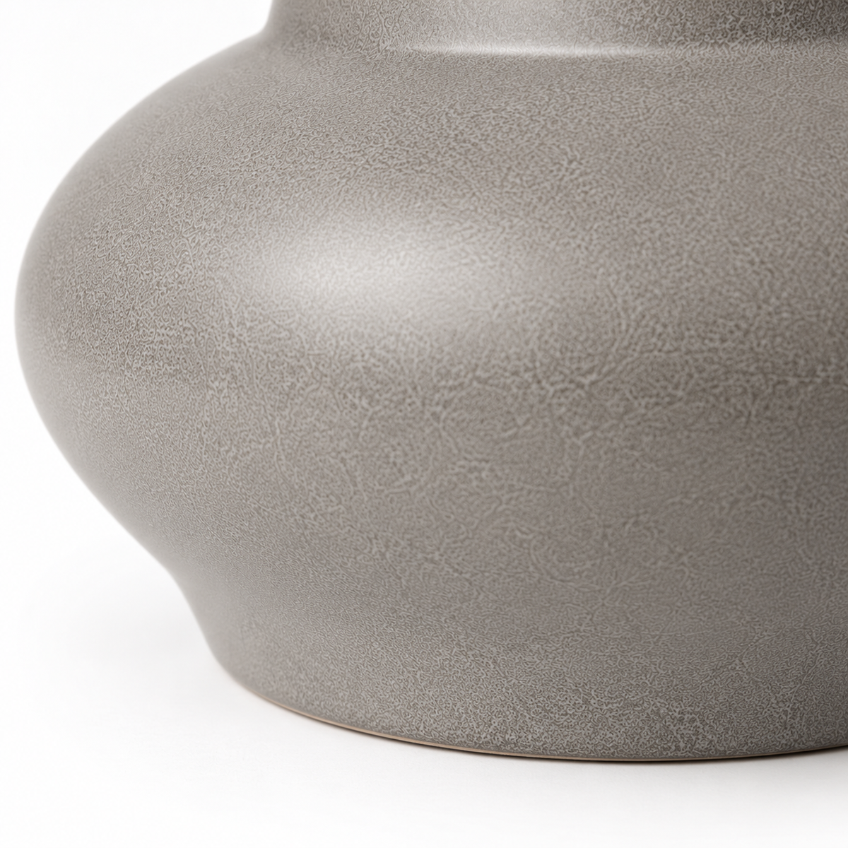 Close-up of rounded gray ceramic vase form and base