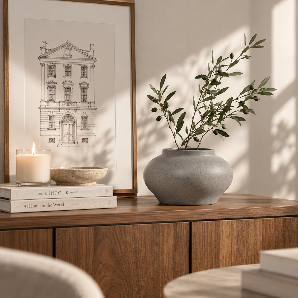 Gray ceramic vase with leafy branches styled on a wood console